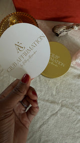 Hand holding a white card with 'Club Affirmation' branding on a textured surface.