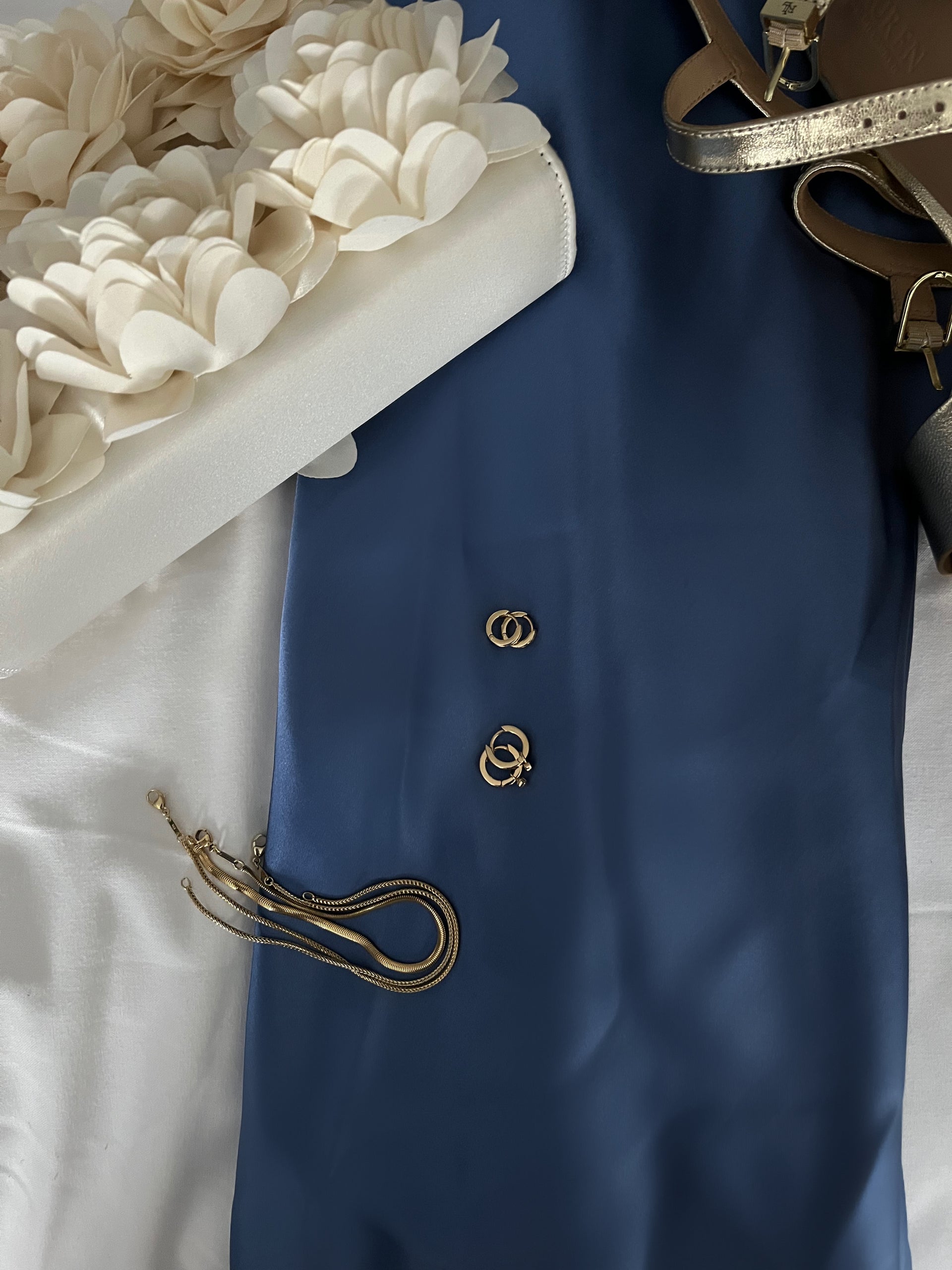 Blue fabric with gold buttons and a white floral arrangement on a white surface